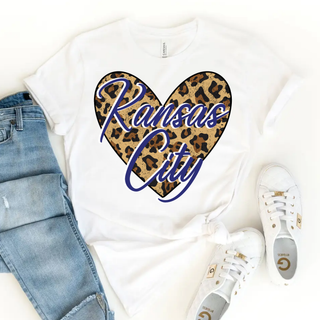 Kansas City leopard heart graphic top Bella Canvas white shirt with blue Kansas City script over leopard print heart styled with jeans and white sneakers