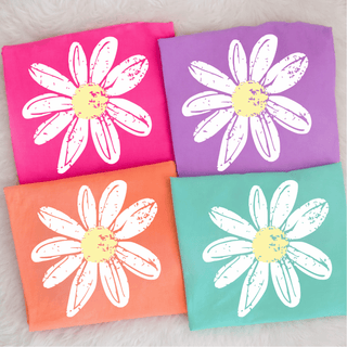 Distressed Daisy Comfort Colors Top shown in four colors, Neon Pink, Violet, Neon Cantaloupe, and Chalky Mint, each with oversized white distressed daisy graphic and yellow center