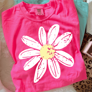 Distressed Daisy Comfort Colors Top in Neon Pink with oversized white distressed daisy graphic and yellow center, folded flat lay with Chalky Mint tee visible behind