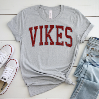 Lifestyle image with rolled sleeves, jeans, and sneakers: Distressed Seaman Vikes Top styled with rolled sleeves, light wash jeans, and white sneakers showing casual school spirit outfit