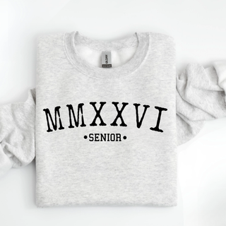 MMXXVI SENIOR black text printed on ash grey Gildan Heavy Blend crewneck sweatshirt folded flat on white background