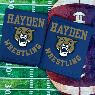 Navy Hayden Wildcats Wrestling stadium blanket with Wildcats mascot graphic and bold gold lettering, folded on football field background