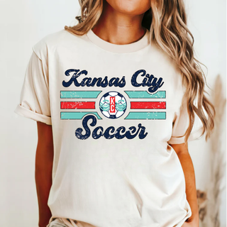 Woman wearing a Kansas City Soccer graphic top with retro striped KC soccer design on the front