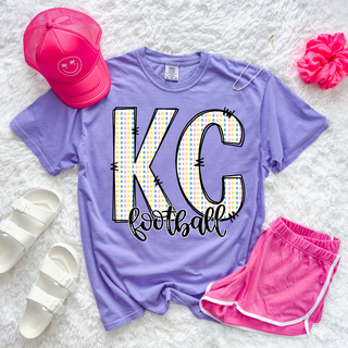 Violet Comfort Colors KC Football shirt featuring pastel egg pattern letters with stitched outline graphic styled with pink shorts and accessories.