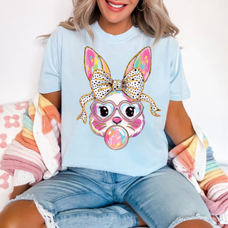 Woman wearing light blue Bubble Bunny Bliss Graphic Tee featuring colorful bunny with bow, glasses, and bubble gum detail
