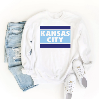 Kansas City stripe block graphic top featuring bold blue horizontal bars and layered city lettering on a white unisex style sweatshirt
