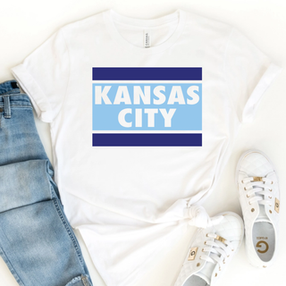 Kansas City stripe block graphic top featuring bold blue horizontal bars and layered city lettering on a white unisex style