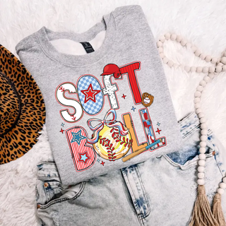 Heather grey sweatshirt with colorful retro softball graphic featuring bold SOFTBALL lettering, bow, bat, glove, and baseball details styled flat lay with denim and accessories