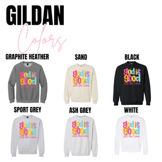 Gildan God Is Good All The Time top shown in graphite heather, sand, black, sport grey, ash grey, and white options featuring a bold colorful Christian faith graphic with retro floral accents.