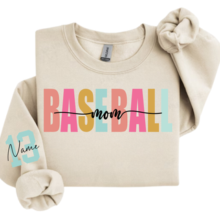 Personalized baseball mom name and number graphic Gildan sweatshirt in sand featuring bold varsity style baseball mom lettering with custom player name and number on the sleeve.