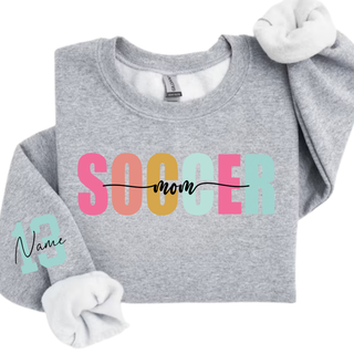 Soccer Mom personalized sweatshirt with blue print lettering and custom sleeve number, shown on a heather grey crewneck.