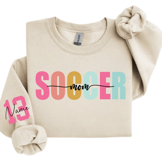 sand crewneck sweatshirt with pastel Soccer Mom graphic and custom pink sleeve number personalization.