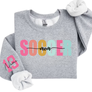 sport grey crewneck sweatshirt with pastel Soccer Mom graphic and custom pink sleeve number personalization.