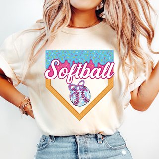 Ivory top featuring a vibrant Softball ice cream drip graphic designed as a home plate with sprinkles, pink script Softball lettering, and a detailed softball bow illustration centered inside the plate design.
