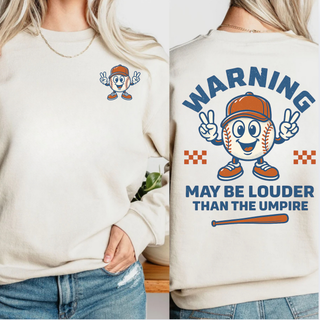 Unisex baseball top featuring a small baseball mascot on the front left chest and a large back graphic reading Warning May Be Louder Than The Umpire with cartoon baseball character and bat design.