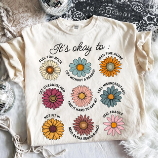 Ivory It’s Okay To mental health affirmation shirt with colorful floral design promoting emotional wellness