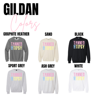 Tanned and Tipsy graphic Gildan crewneck and long sleeve tops shown in graphite heather, sand, black, sport grey, ash grey, and white with distressed pink, blue, and yellow lettering.