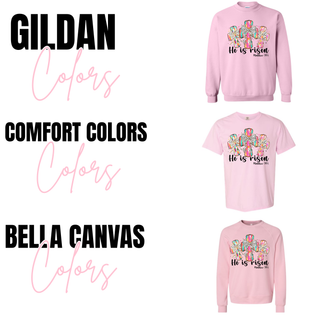 He Is Risen Easter cross Christian top available in Gildan, Comfort Colors, and Bella Canvas styles in pink with colorful patterned crosses and Matthew 28:6 scripture design