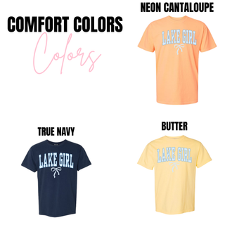 Comfort Colors Lake Girl unisex graphic top available in neon cantaloupe, true navy, and butter featuring light blue varsity lettering with a white bow underneath.