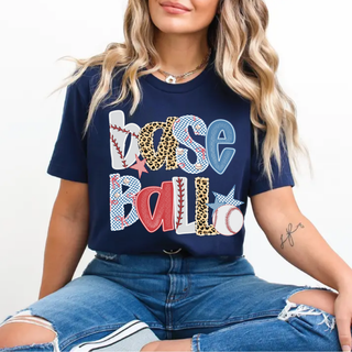 Woman wearing navy Bella Canvas top featuring Base Ball lettering in red, blue, leopard, and baseball stitch patterns with star accents.