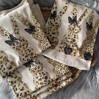 Leopard print Easter bunny graphic sweatshirt folded flat lay featuring three bunny silhouettes with black bows on a neutral sand crewneck.