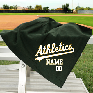 Topeka Athletics Baseball custom stadium blanket with Athletics script logo and personalized name and number displayed on dark green blanket at a baseball field.