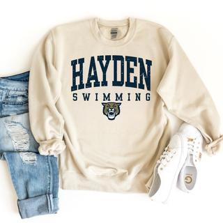 Hayden Swimming classic arch top sand crewneck with navy lettering and wildcat mascot styled with light wash distressed jeans and white sneakers
