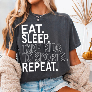 Eat sleep take kids to sports repeat graphic top with bold white text on dark grey shirt styled with denim shorts