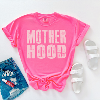 Motherhood distressed graphic on neon pink shirt styled flat lay with denim shorts white sandals and accessories