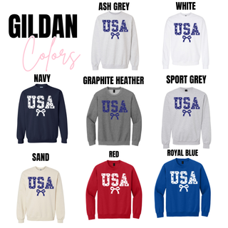 gildan vintage usa stars graphic sweatshirt and tee color options showing navy, graphite heather, sport grey, ash grey, white, sand, red, and royal blue styles with usa star filled lettering and bow graphic displayed on crewneck sweatshirts