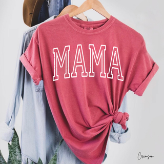 Crimson red graphic top featuring large white varsity “MAMA” lettering, styled on a hanger with a chambray button-up layered behind it, knotted at the hem for a casual everyday outfit look