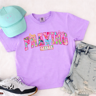 Praying Mama Floral Bow Comfort Colors T-Shirt in  neon Violet tee with bright floral patterned letters and bow accents, styled flat lay with distressed denim shorts, sneakers, and mint trucker hat