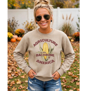 Woman wearing tan Agriculture is the Backbone of America crewneck sweatshirt with corn graphic design outdoors in fall