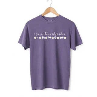 Agriculture Teacher graphic design in white script with farming icons on an adult violet Comfort Colors short sleeve t-shirt.