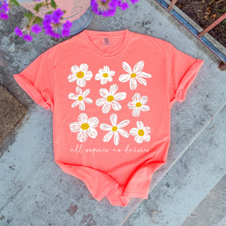 Neon Red Orange Comfort Colors tee with a distressed white daisy cluster graphic and the words all oopsies no daisies laid flat outdoors with purple flowers in background