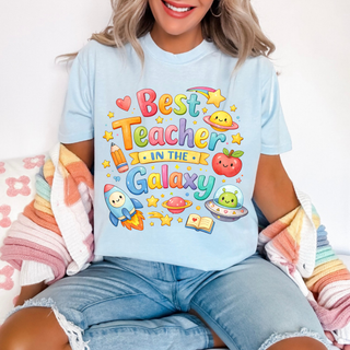 Woman wearing chambray tee with Best Teacher In The Galaxy rainbow space design, rocket, apple, stars, adult unisex