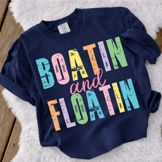 Navy Comfort Colors Boatin and Floatin tee with multicolor distressed block letter design laid flat