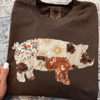  Folded espresso brown Comfort Colors t shirt with boho patchwork pig graphic featuring floral sun and cow print quilt pieces with white stitching detail