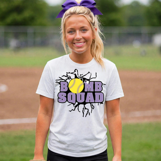 Woman wearing a white Bomb Squad yellow softball logo top at a softball field