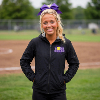Woman wearing black Bomb Squad Yellow Softball Logo waterproof jacket at a softball field