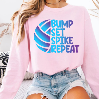 Model wearing light pink crewneck with BUMP SET SPIKE REPEAT blue purple gradient volleyball graphic front view

