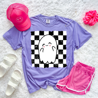 purple adult graphic tee with cute ghost on black and white checkered background, halloween flat lay with pink accessories
