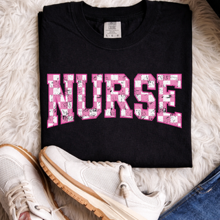 Folded black tee with NURSE pink checkered distressed varsity arch letters front view flat lay
