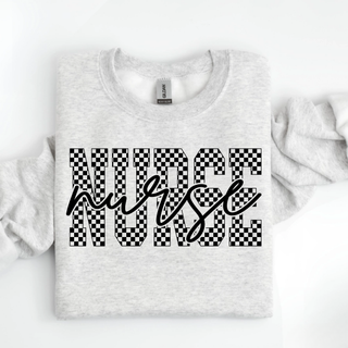 Ash grey crewneck with Nurse in checker block letters and nurse in script overlay folded flat on white background
