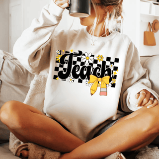 White crewneck sweatshirt with checkered Teach, daisies, and yellow pencil bow, cozy lifestyle