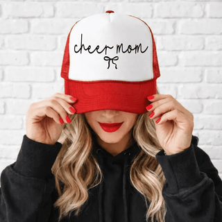 Red and white trucker hat with script cheer mom and bow, worn on head