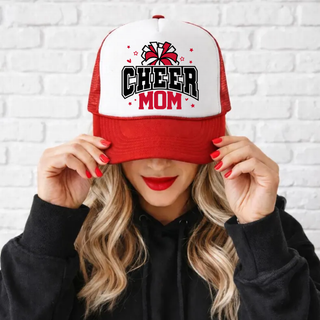 Red and white trucker hat with CHEER MOM in black varsity letters and red MOM, red and white pom pom, red stars and hearts on white front panel, red mesh back and bill, worn by woman with red lipstick