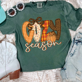 Comfort Colors moss tee with patterned cozy season lettering in plaid floral and leopard print with leopard bow and pumpkin accent
