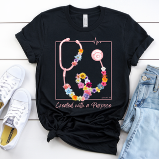 Black Bella Canvas tee with pink floral stethoscope and Created with a Purpose design styled flat lay with sneakers and denim