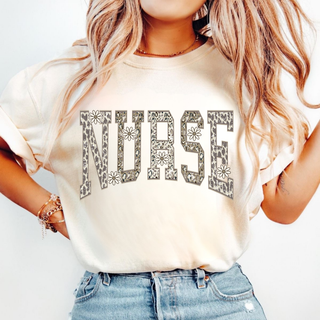 Model wearing ivory top with NURSE in daisy leopard varsity letters, lifestyle shot
